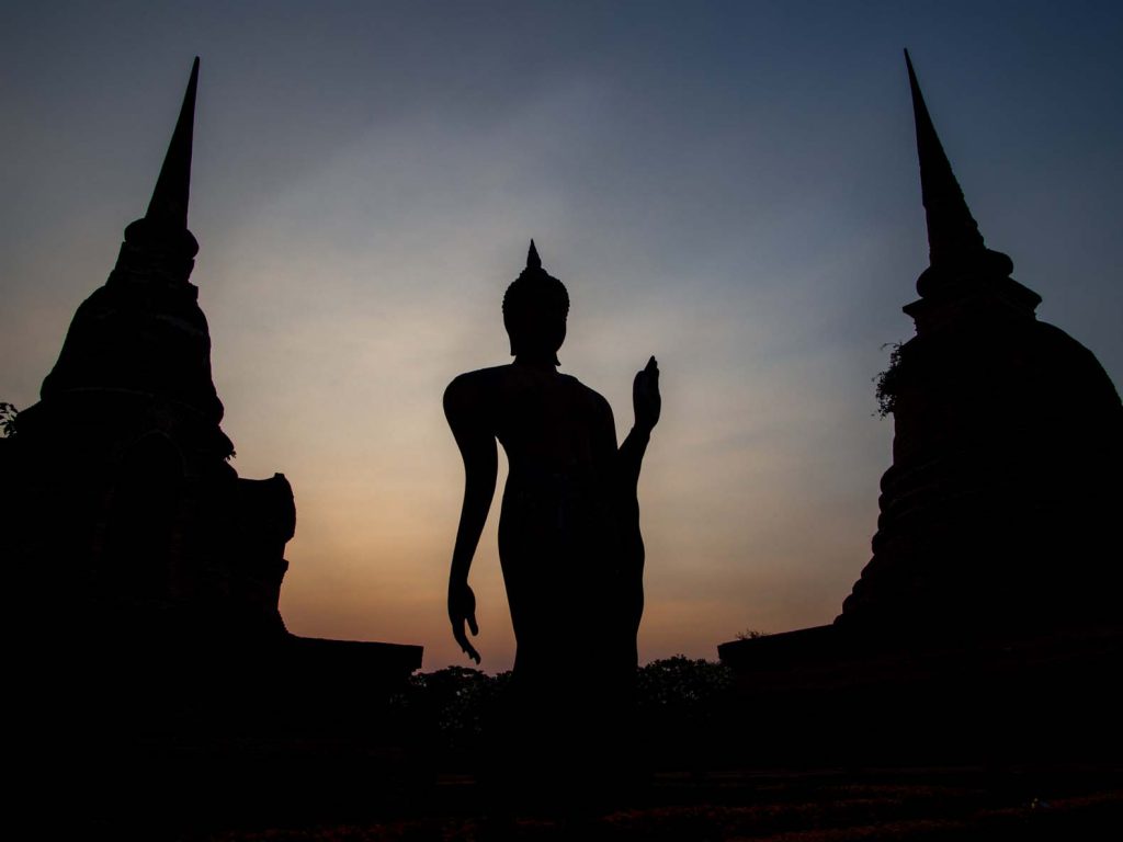 Buddha statue and stupas at sunset at Sukhothai historical park